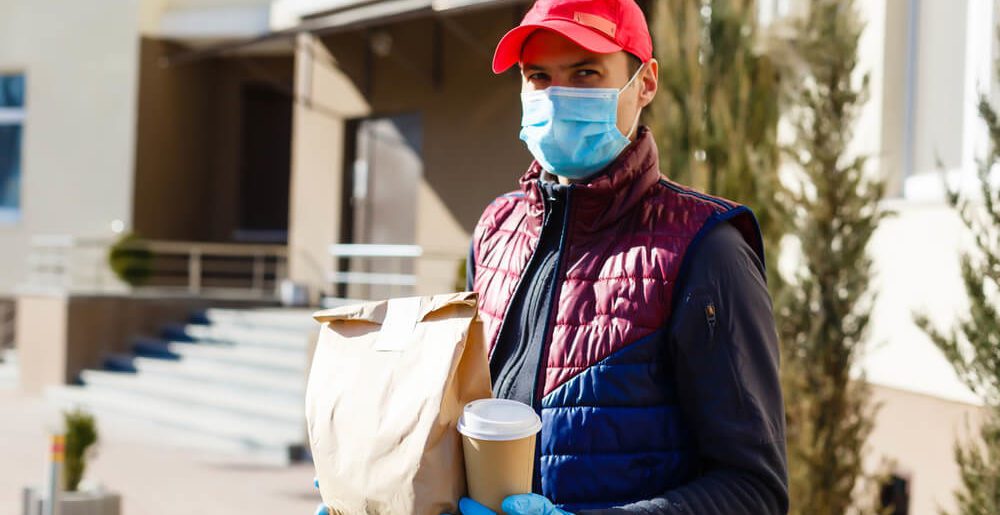 Food delivery person with mask and gloves. Many restaurants switched to delivery services during Covid-19 shutdowns, causing insurance worries.